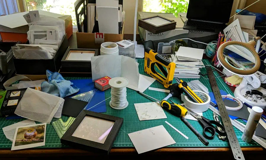 Judi's messy work desk with framing supplies