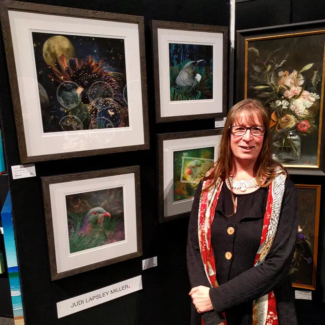 Photo of Judi in front of four framed prints in an exhibition.