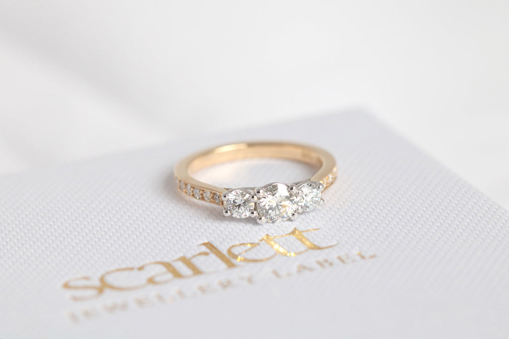 yellow gold engagement ring featuring three round brilliant cut diamonds