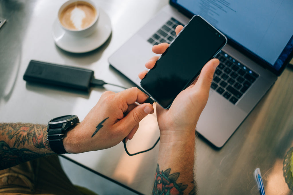 homme branchant un téléphone à une batterie portative