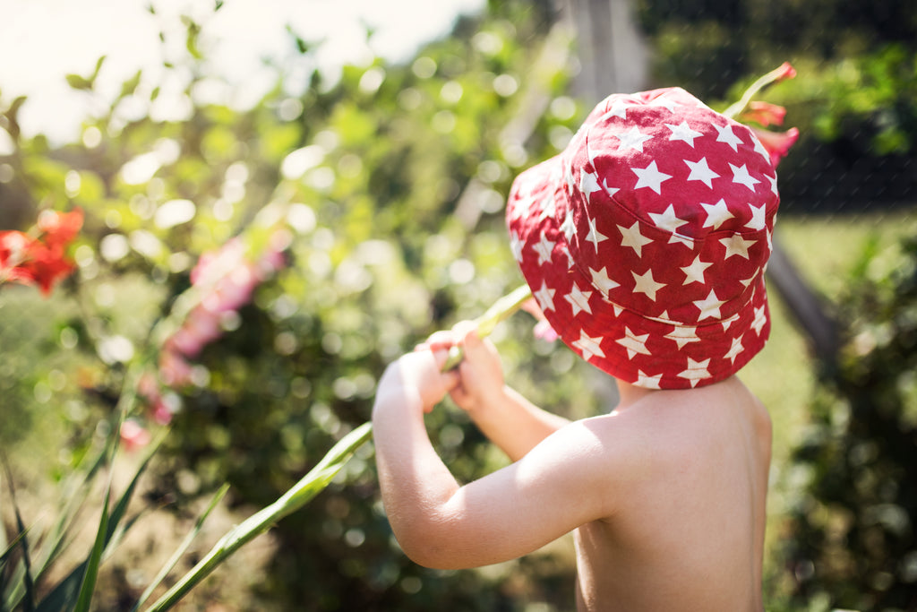 Enfant portant un bob rouge dans un jardin