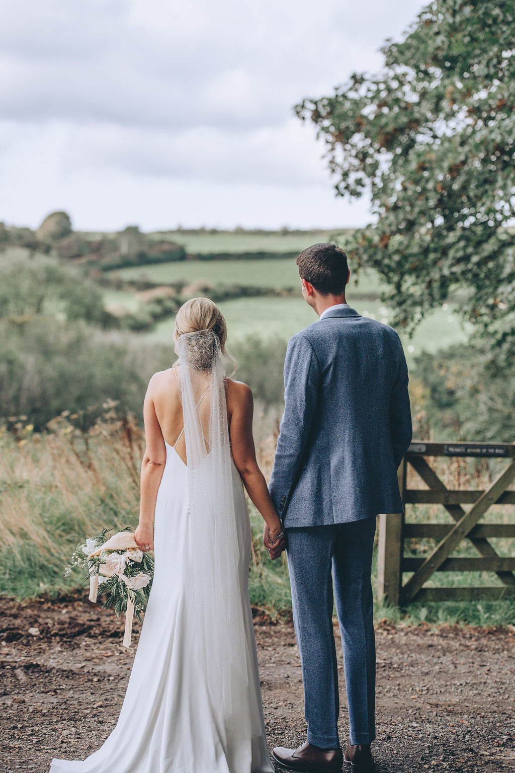 couple holding hands looking into meadow Trevenna barns