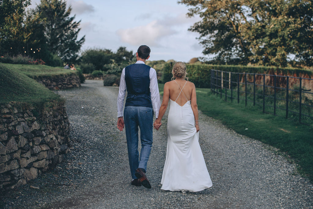 Couple walking away holding hands at Trevenna barns