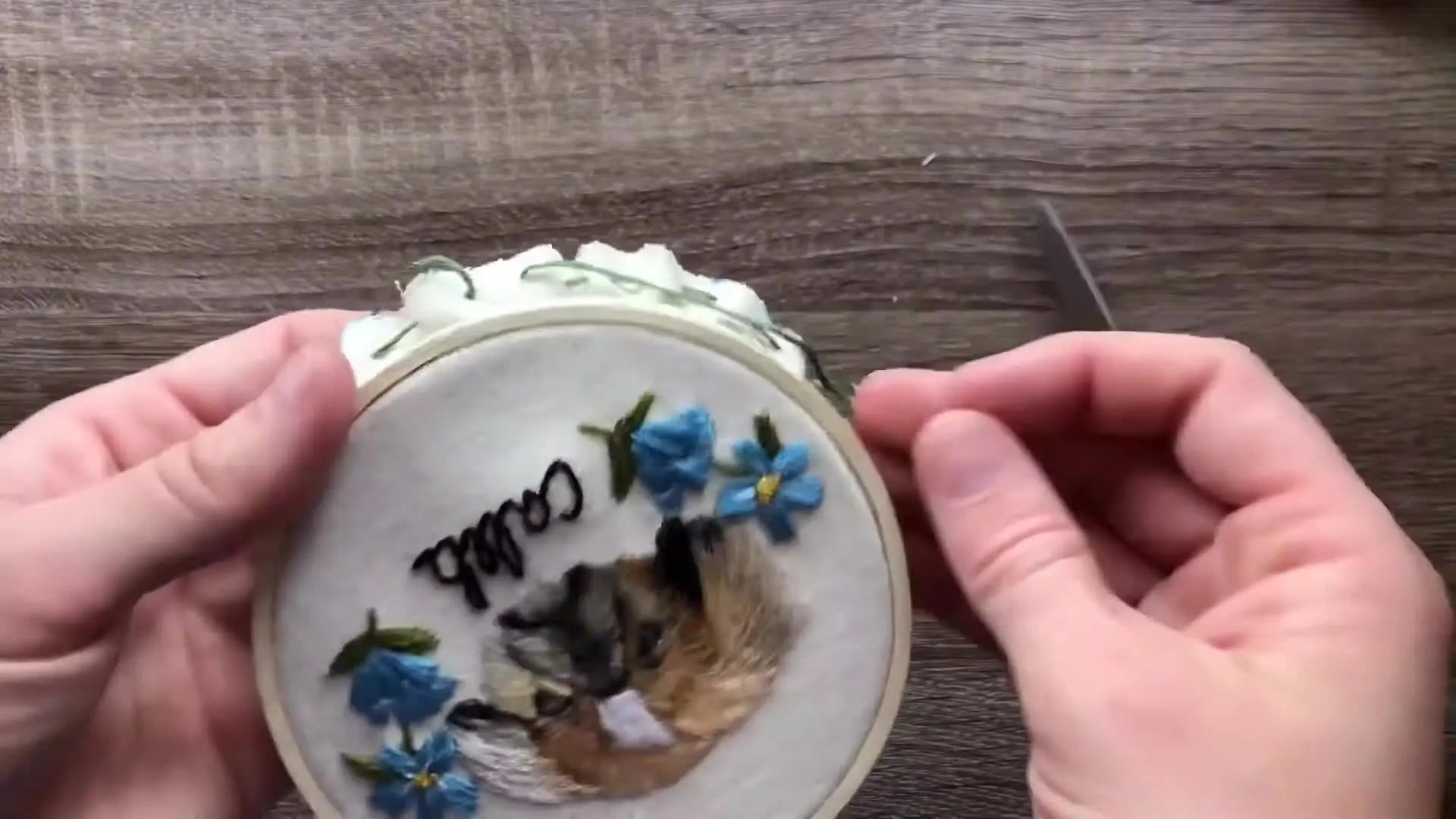 The back of the hoop displaying a complete running stitch around the entire circumference of the fabric, before being pulled tight.