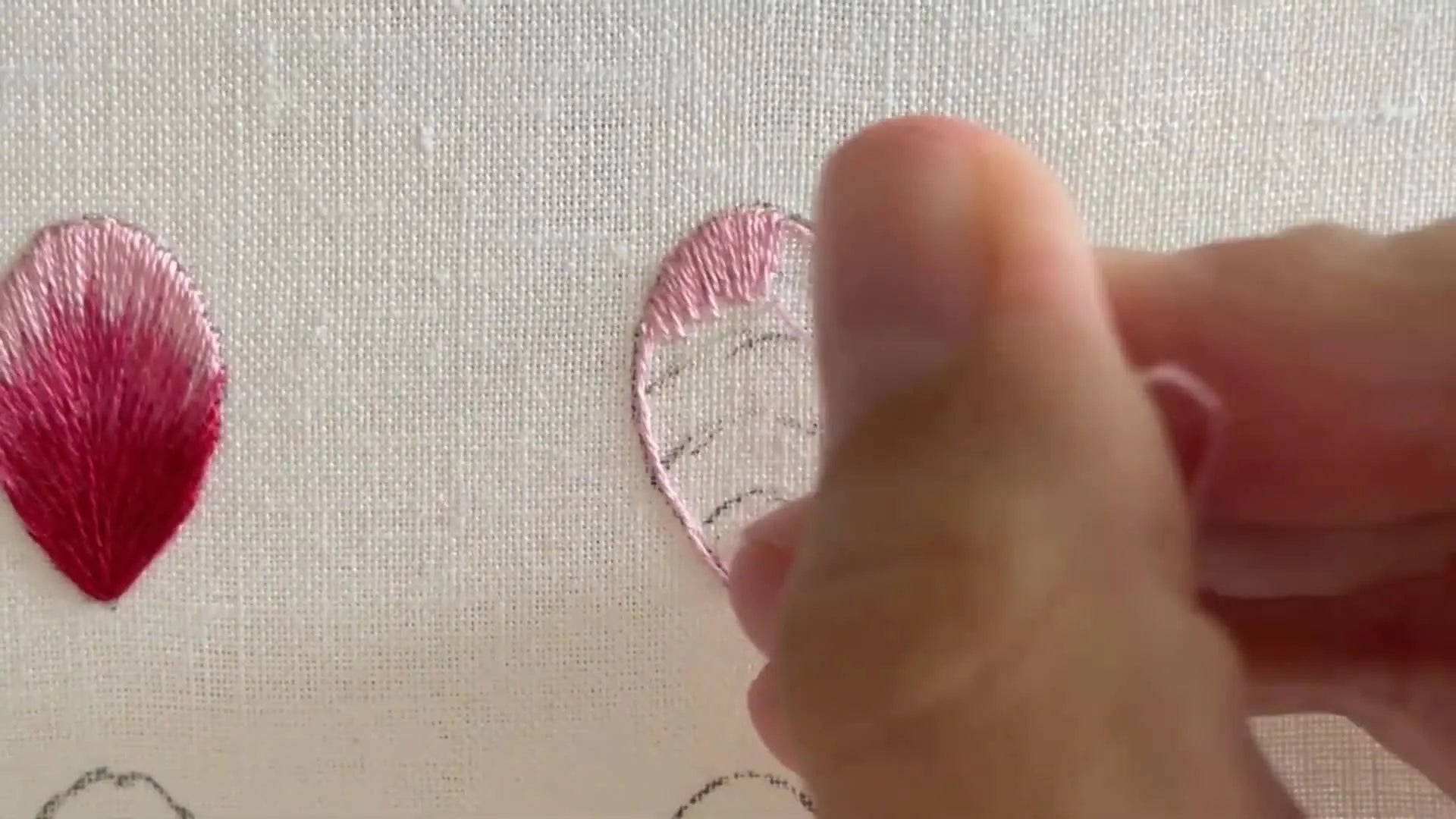 The top section of the petal is partially filled with varying lengths of short and long stitches in the lightest pink color.