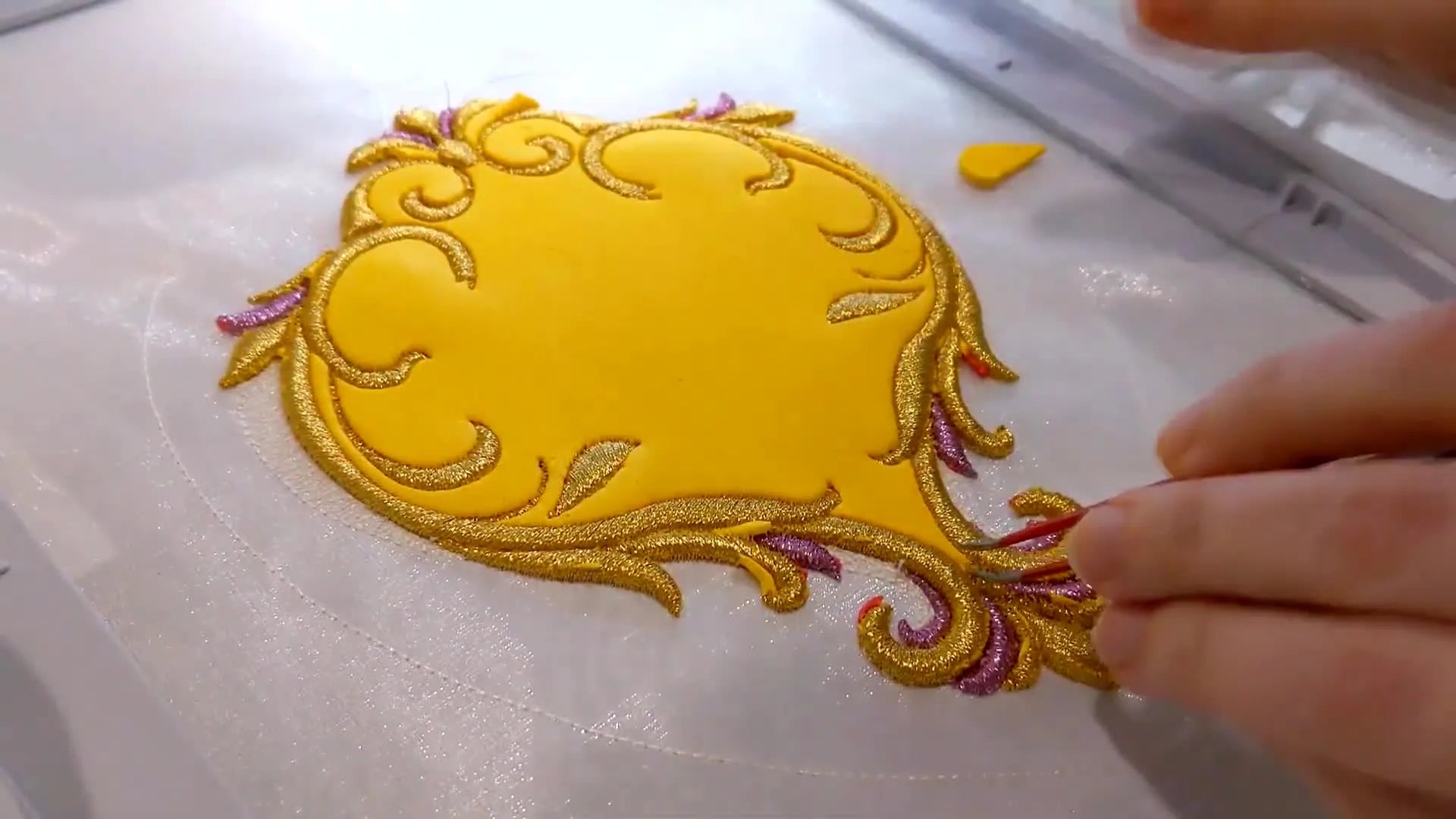 Tweezers meticulously removing small pieces of foam trapped between intricate stitches.