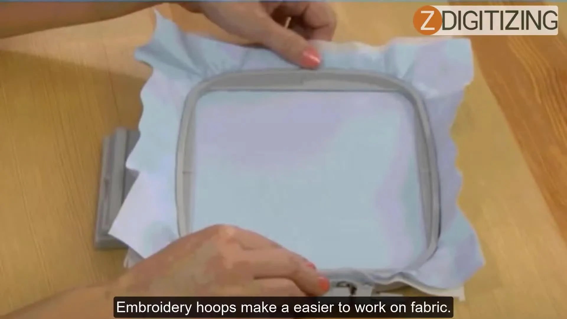 Hands gently pressing fabric onto an inner embroidery hoop with an outer hoop nearby, preparing for embroidery.