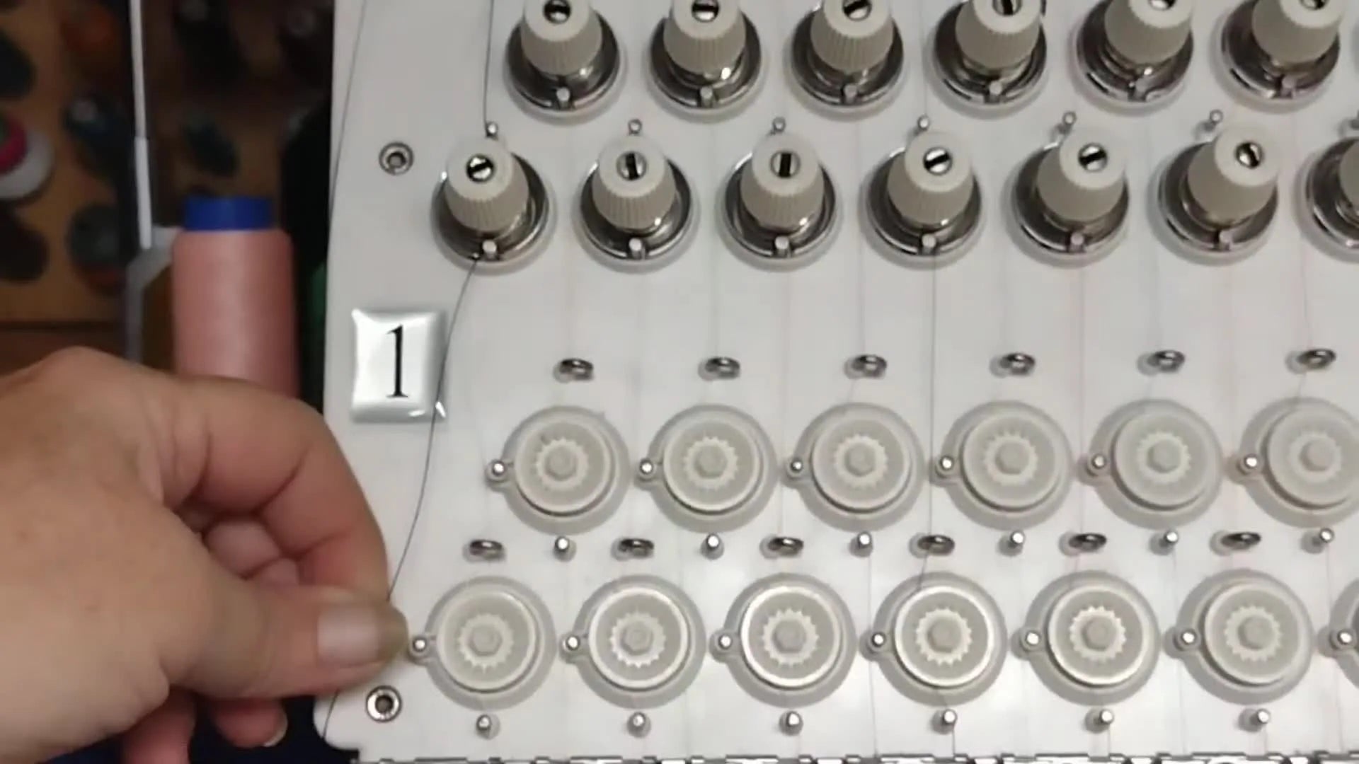 Hand guiding thread to the right of a small peg and into an opening on the lower tension disc housing.