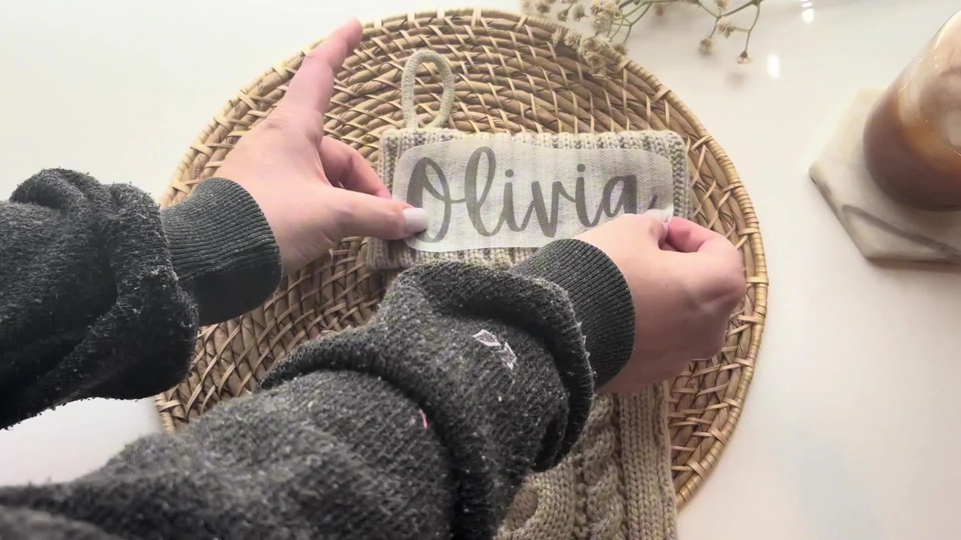 Hands pressing the name pattern onto the stocking cuff.