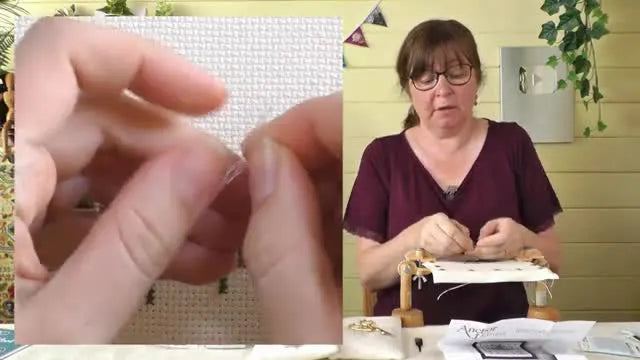Close-up of hands separating a single strand of pale blue linen embroidery thread from a larger group of strands.