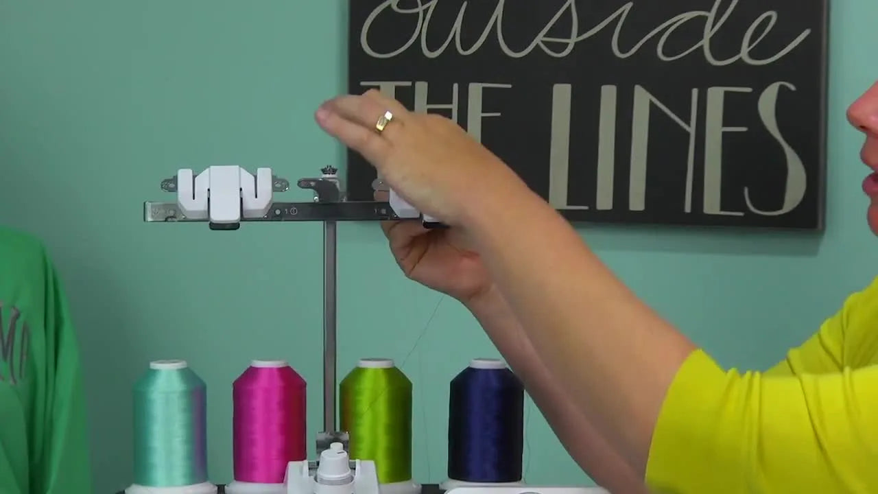 A hand guiding green thread through the first guide on the thread antenna to stage it for later use.