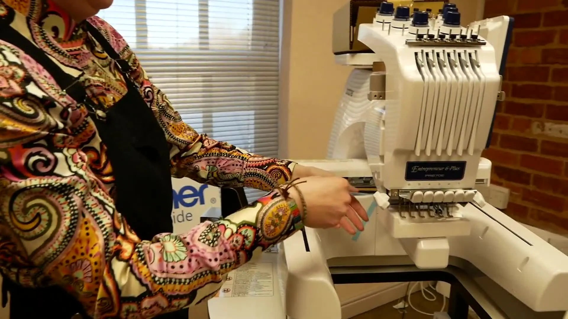 Close-up of hands peeling blue protective tape from the machine's arm.