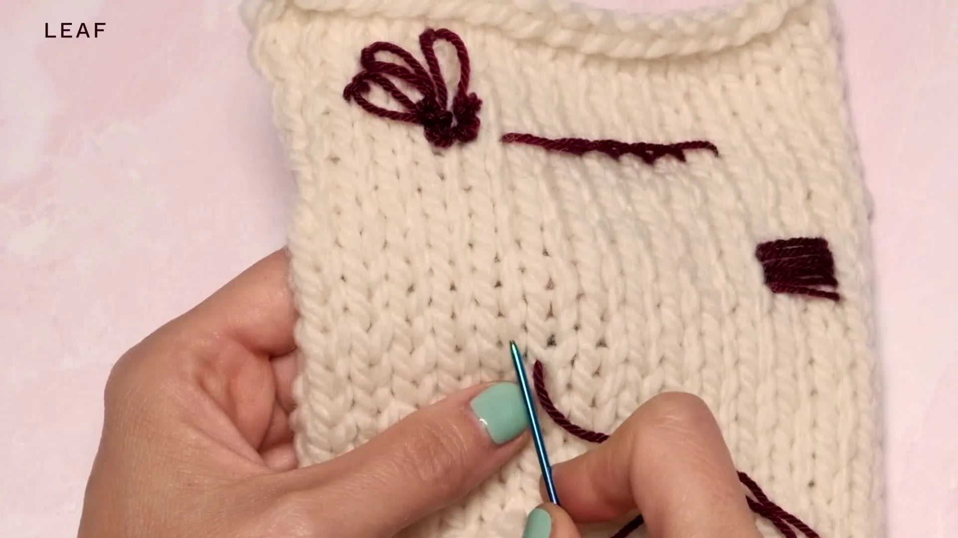 A darning needle creating a diagonal stitch from the center outwards, forming one side of a leaf.