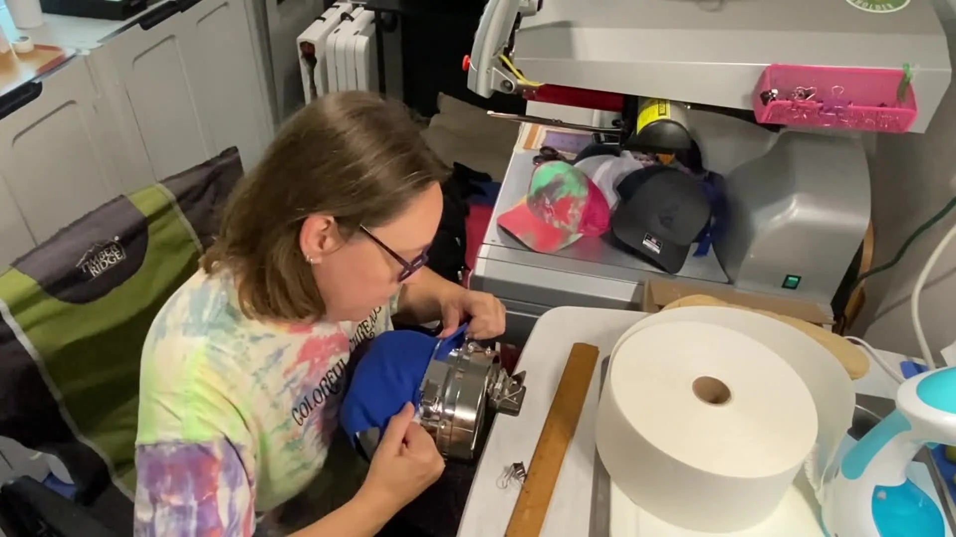 Hand pulling the side of the blue hat taut to remove any wrinkles before clipping.