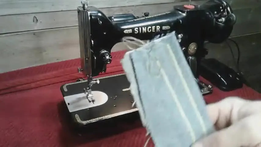 Hand holding a folded piece of denim with yellow zigzag stitches