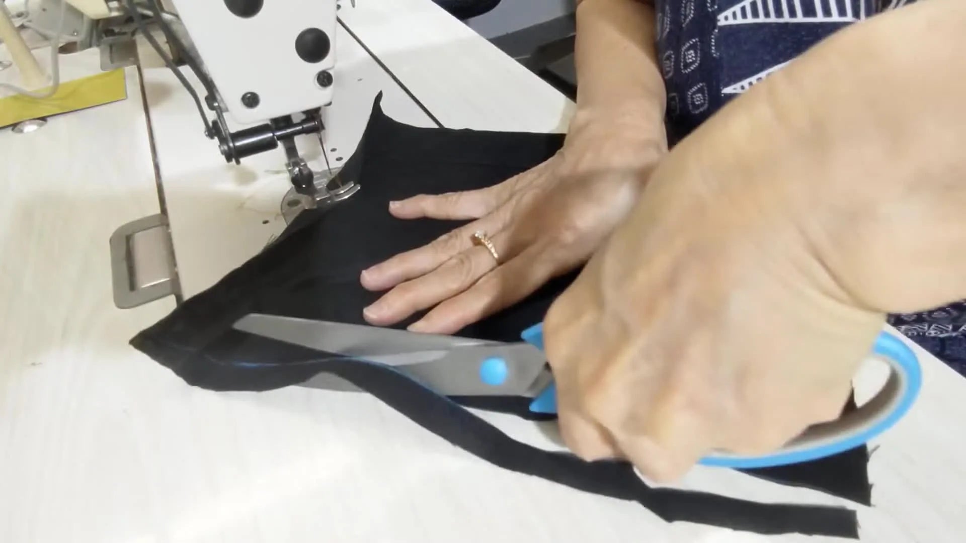 Scissors cutting along a chalk line on black fabric.