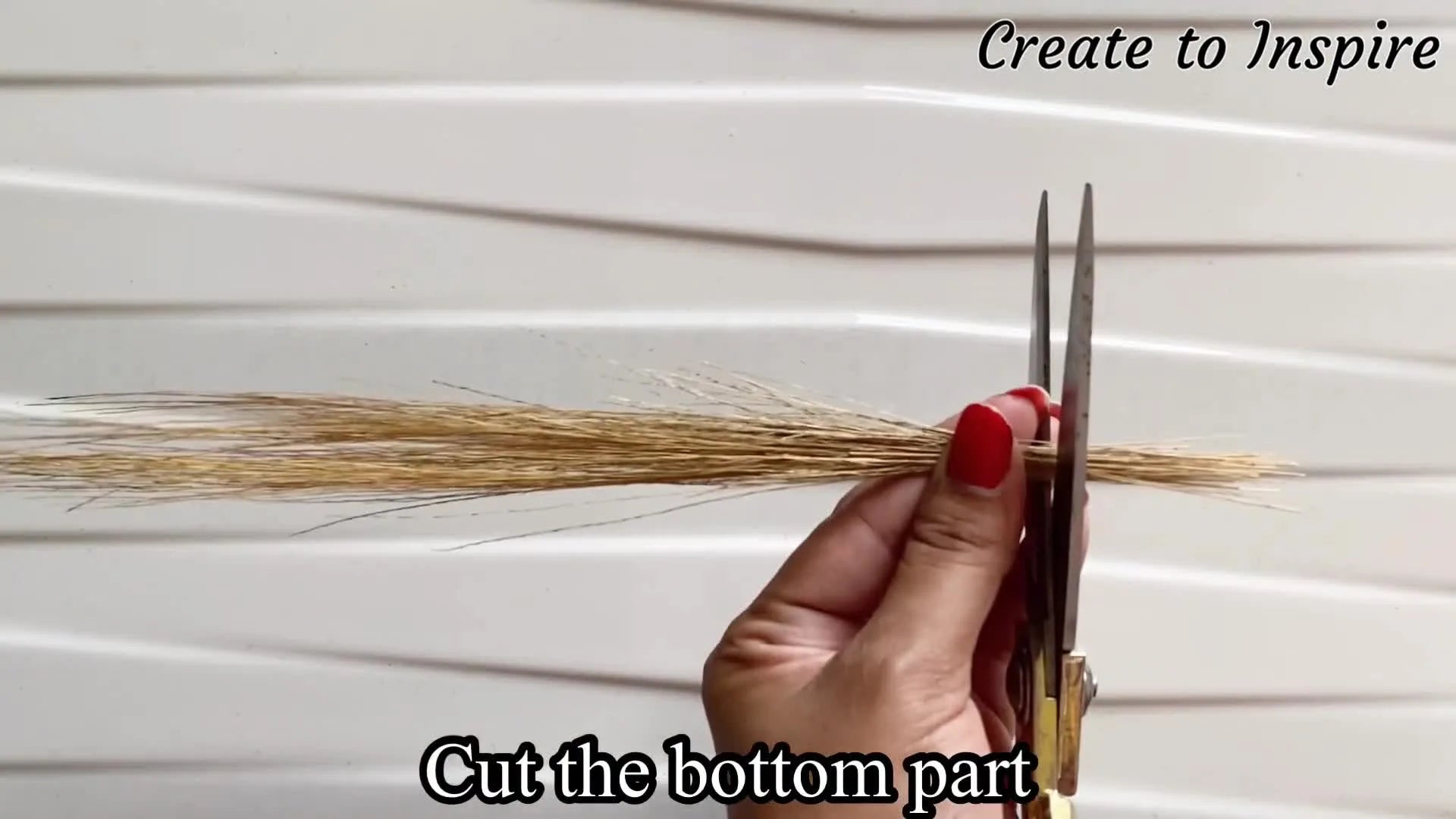 Scissors cutting the bottom of broomstick bristles.