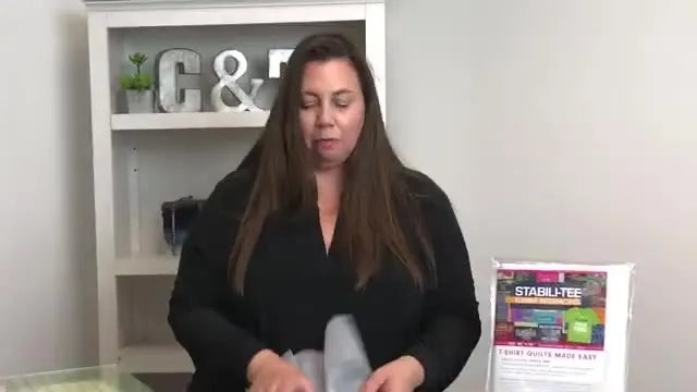 A piece of white, semi-transparent fusible interfacing is held up.