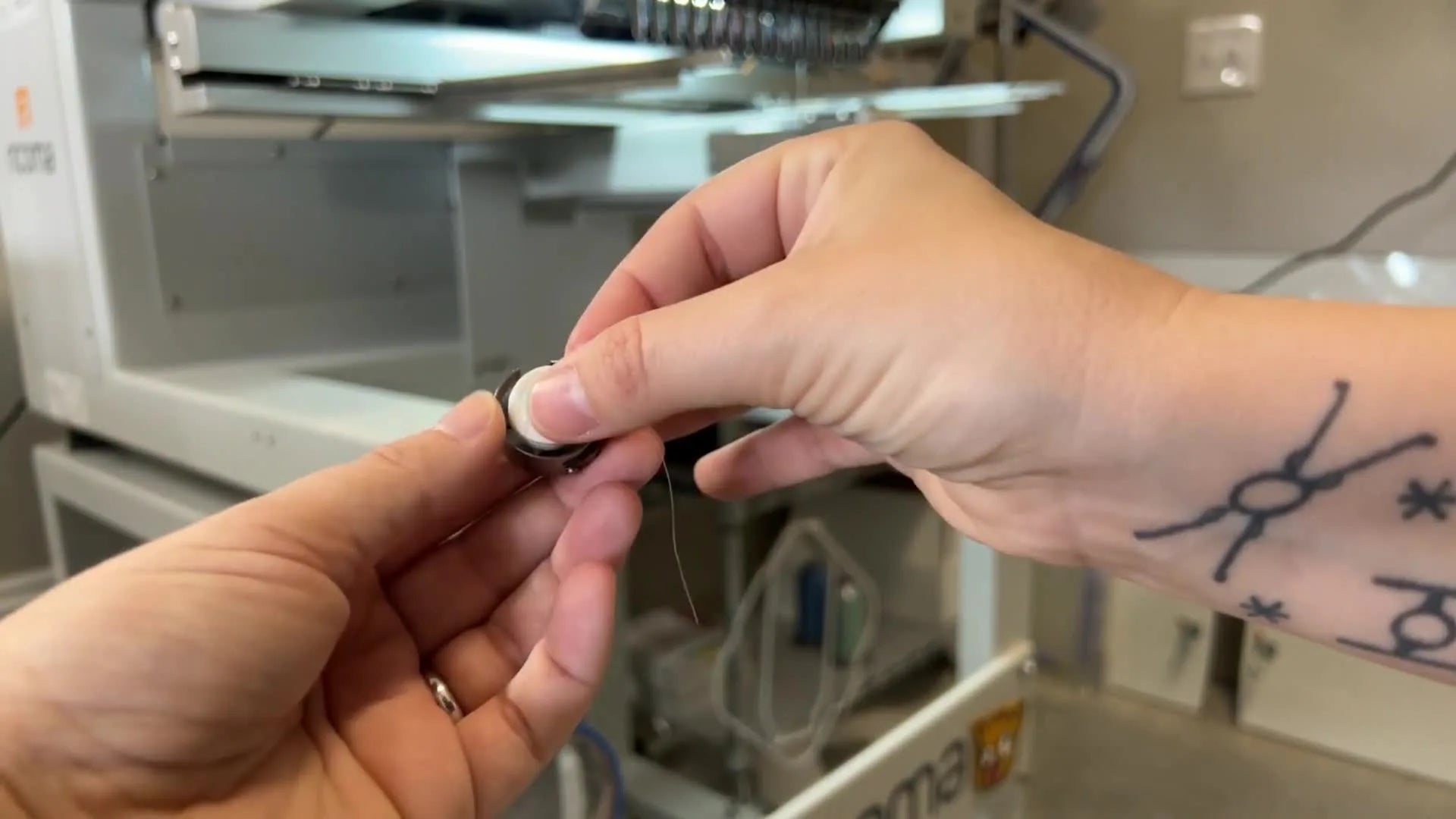 Hands winding the bobbin thread twice around the pigtail spring on the bobbin case for proper tension.