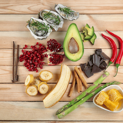 The image is a table full of various fruits and vegetables like zucchini and cucumber. The setting is indoors on a wooden table.