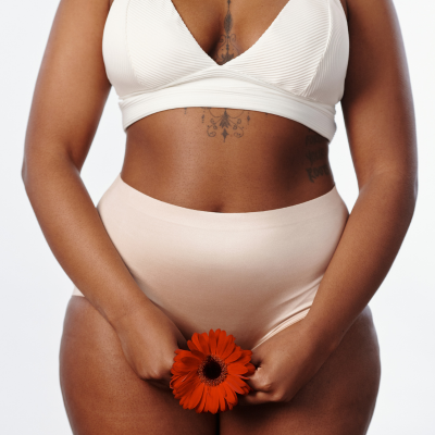 The image features a woman with a flower placed on her pelvis.