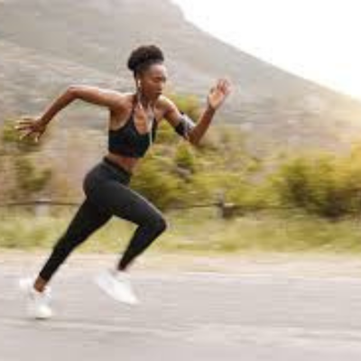 The image shows a person running on a road. It features a woman engaged in physical fitness through running. The setting is outdoors, possibly a marathon or individual sports event. The person is wearing appropriate clothing and footwear for running on the road.