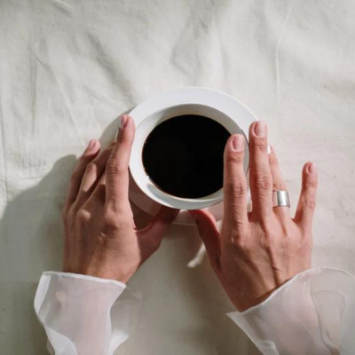 The image is of hands holding a cup of coffee.