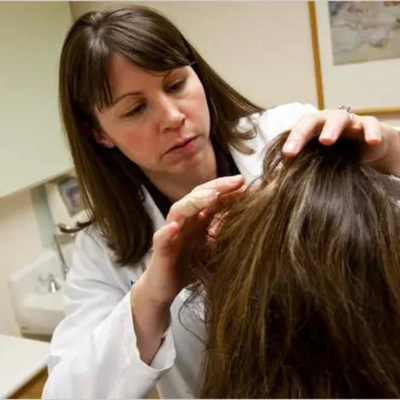 A hair dermatologist checking the person's scalp.