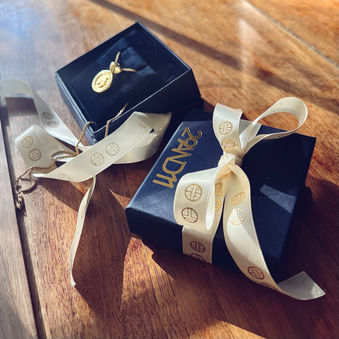 29 AND 11 luxe navy box with a gold logo stamp.  TE logo embossed in gold on satin cream ribbon circles the box.