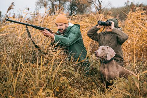 Father and son sitting in a bushes and hunting down an animal
