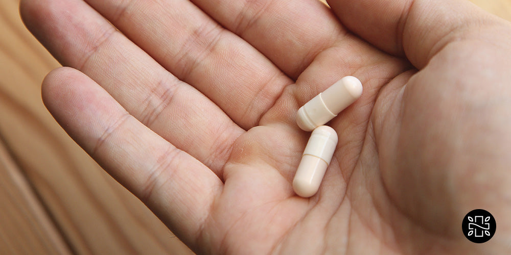 2 white capsules on a hand