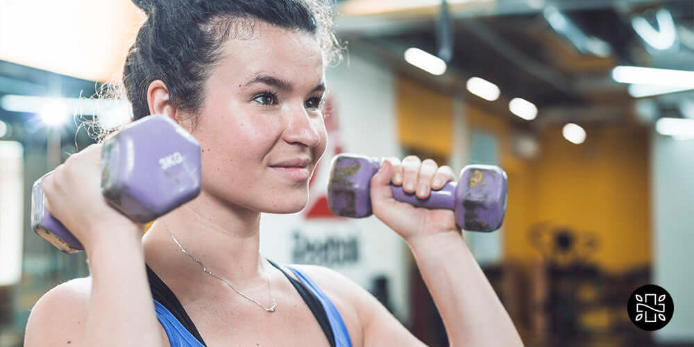 Mujer joven atlética haciendo ejercicio con mancuernas