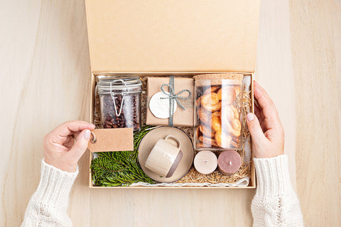 A cardboard box with jars and small paper wrapped gifts