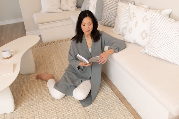 Catherine sits on the floor, leaning against a sofa, and reading her journal.