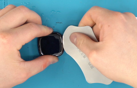 Dipping your thin metal pry tool in rubbing alcohol before inserting it between the screen and housing in order to remove the screen from this FitBit Versa 4 fitness tracker