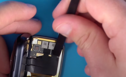 Using a plastic spudger to secure the black tape over the ribbon cables on the back of the Series 7 Apple Watch screen