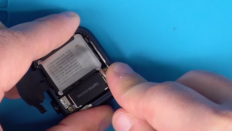 Lifting the battery out of a Apple watch series 7 using a flat head against the metal case