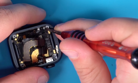 Pressing through each screw hole in the corners of the inside of the Apple Watch Series 7