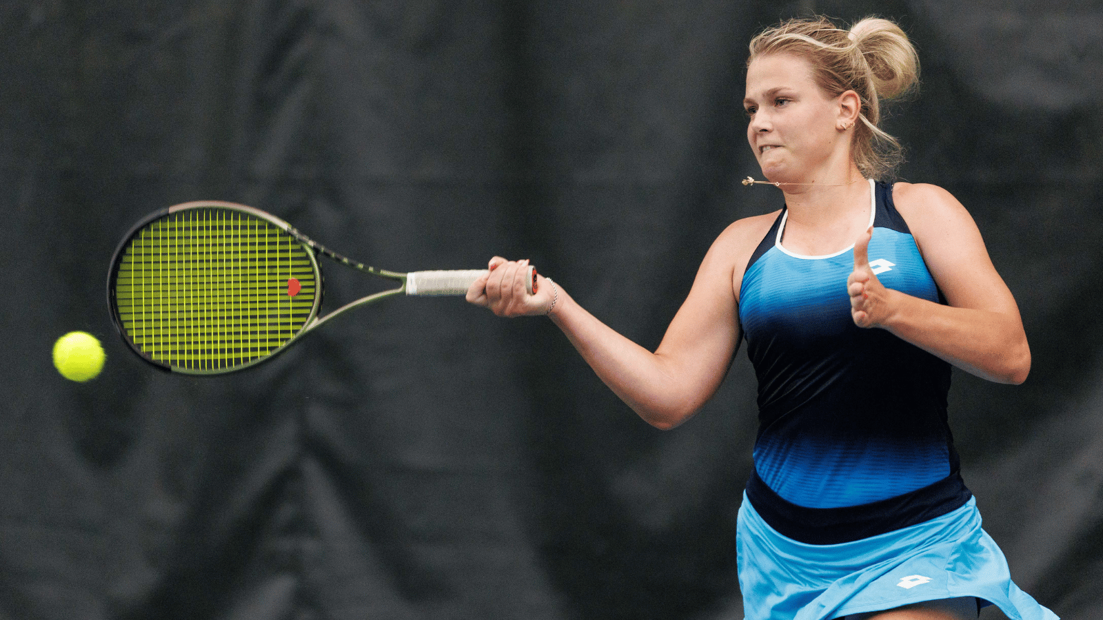 Blonde woman in blue outfit hits forehand