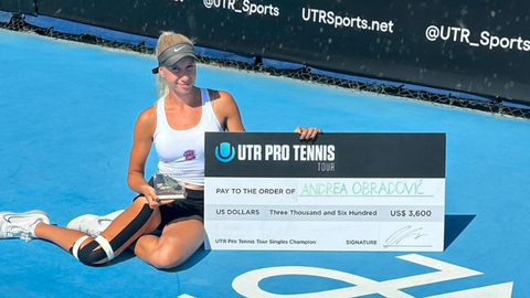 A young woman poses on a blue hard court with her prize money check.