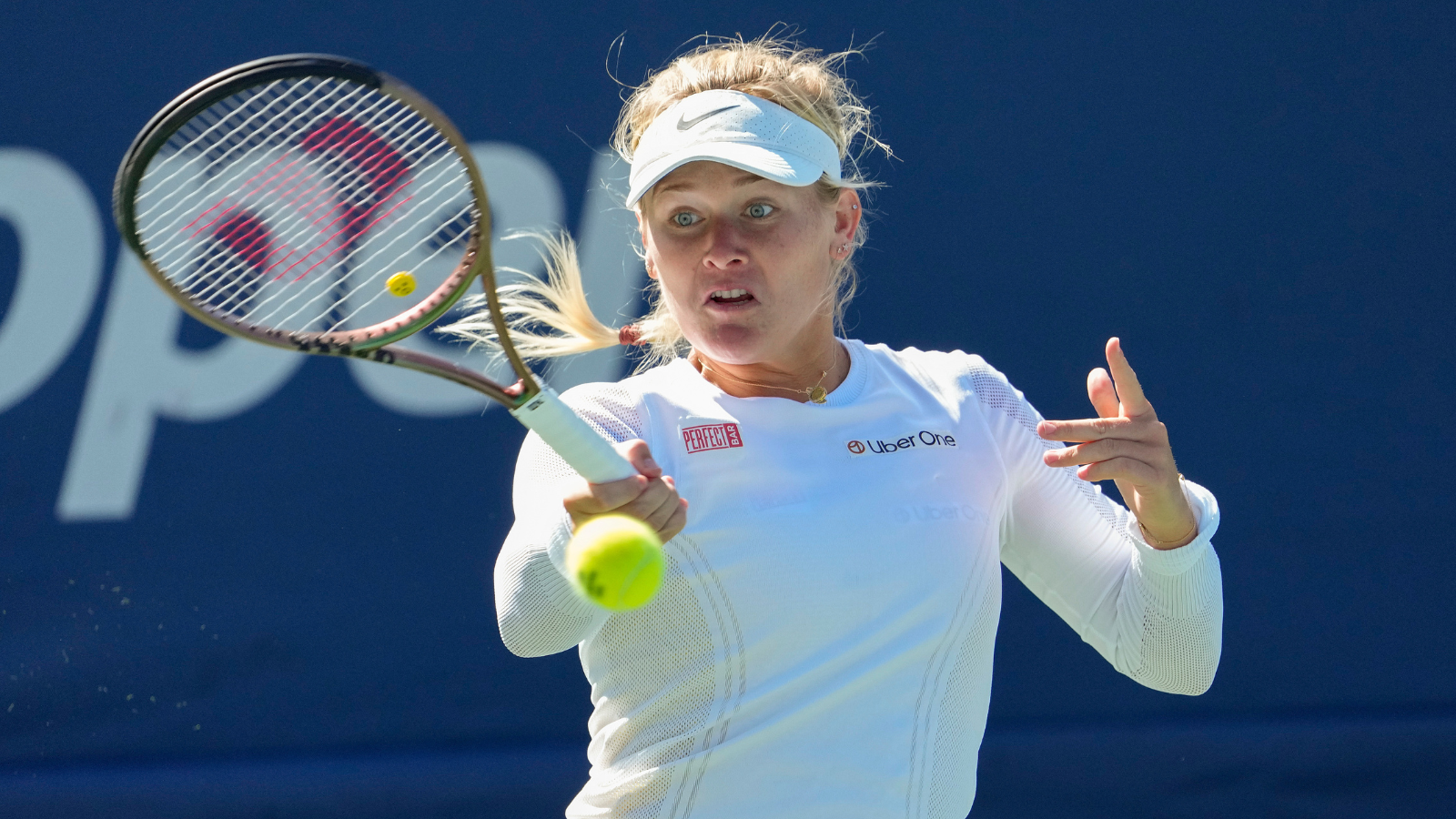 woman in white outfit hits forehand tennis shot