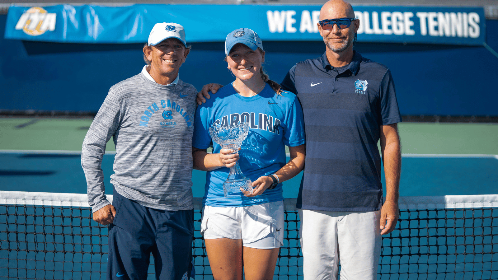 Reece Brantmeier posing with her coaches and trophy.