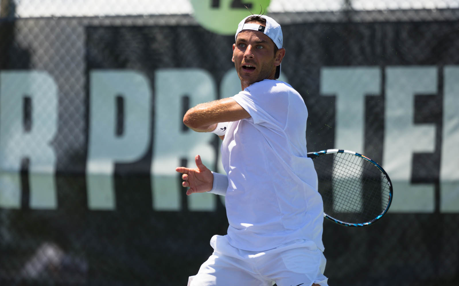 A male tennis player hits a left-handed forehand