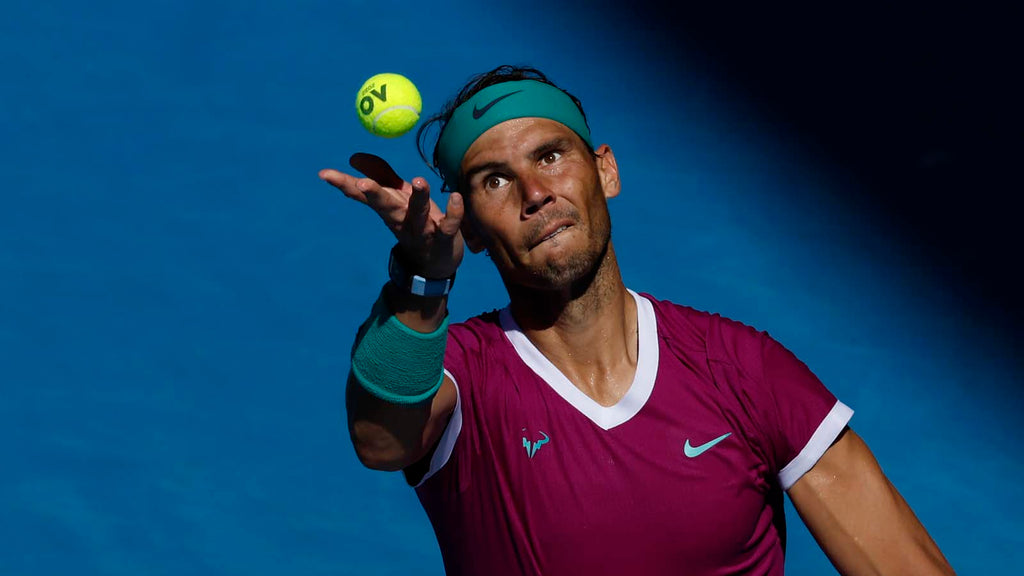 Rafael Nadal prepares to serve during a match while wearing a purple Nike shirt and trying to improve his UTR Rating