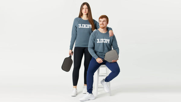 Two models show off pickleball crewneck sweaters.