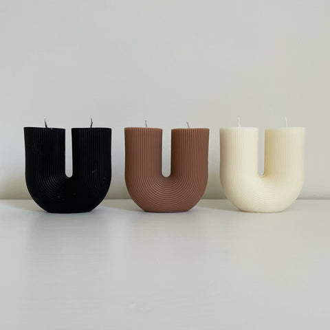 alt="three Ivory white, brown and black U shaped candles"