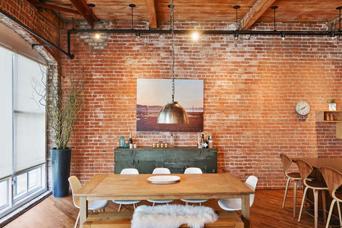 Un mur en brique exposé avec une suspension lumineuse industrielle dans un salon minimaliste
