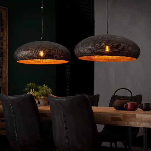 Suspension lumineuse industrielle en métal noir au-dessus d'une table en bois brut