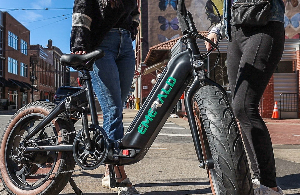 Two people talking by a parked emerald ebike