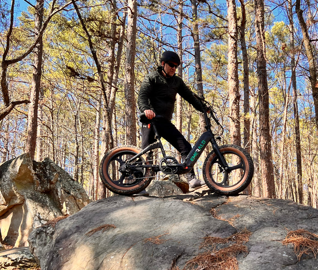 Man holding the Emerald ebike on a rock while on an outdoor ride.